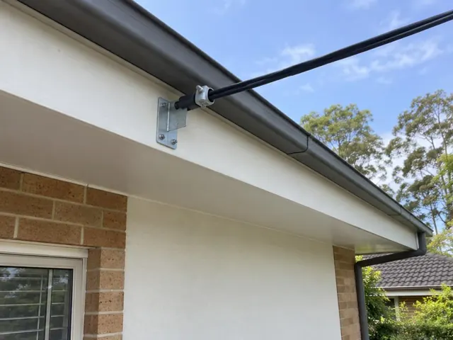 Overhead service cable and bracket on a house eave with brick and rendered walls in Baulkham Hills