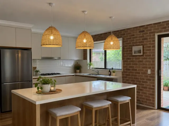 Kitchen with three woven pendant lights above a white island in a brick-walled home in Winston Hills